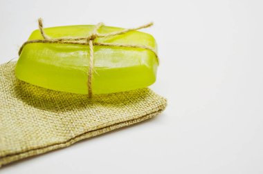 İple bağlanmış yeşil sabun, jüt çantanın beyaz arka planında yatıyor.