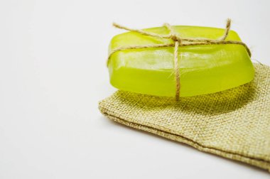 İple bağlanmış yeşil sabun, jüt çantanın beyaz arka planında yatıyor..