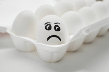 Tepside boyalı üzgün yüzü olan beyaz yumurta..