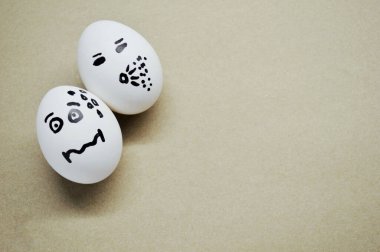 Ahşap arka planda farklı boyalı yüzleri olan beyaz yumurtalar..