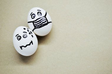 Ahşap arka planda farklı boyalı yüzleri olan beyaz yumurtalar..