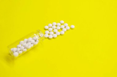 Sarı arka planda fotokopi alanı olan beyaz haplar ve şişe, Sağlıklı ve Tıp Konsepti.