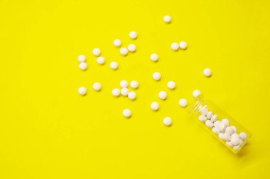 Sarı arka planda fotokopi alanı olan beyaz haplar ve şişe, Sağlıklı ve Tıp Konsepti.