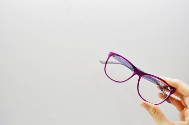 Kadın eli, beyaz arkaplanda fotokopi alanı olan gözlük tutuyor.
