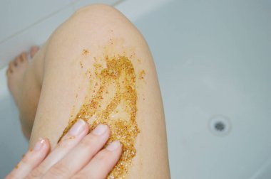 Kahve masajı fırçasıyla kadın bacaklarına yakın çekim. Kozmetik, bakım, kaplıca, güzellik ürünleri, güzellik konsepti ve bikini.