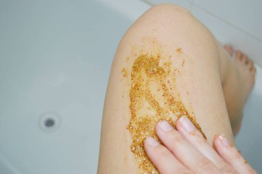 Kahve masajı fırçasıyla kadın bacaklarına yakın çekim. Kozmetik, bakım, kaplıca, güzellik ürünleri, güzellik konsepti ve bikini.