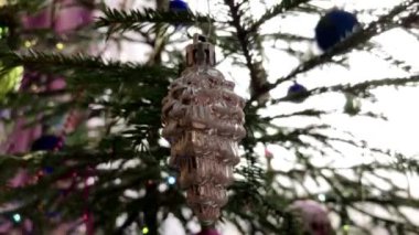 Gümüş kozalaklı Noel oyuncağı köknar ağacında.