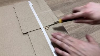 Yeni mobilyaların kutusunu bıçakla açan kadın.