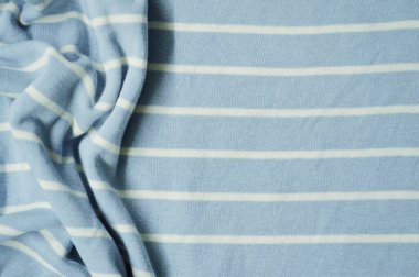 Arka plan olarak beyaz ince çizgili tekstil desenli mavi. Mavi 'ye beyaz çizgili kumaş kumaş kumaşı ile yaklaş. Buruşmuş kumaş dokusu