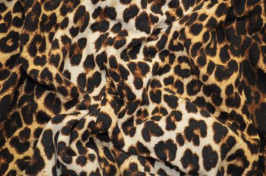 Arka plan olarak leopar desenli tekstil. Leopar desenli kumaşa yakın çekim yap. Buruşmuş kumaş dokusu