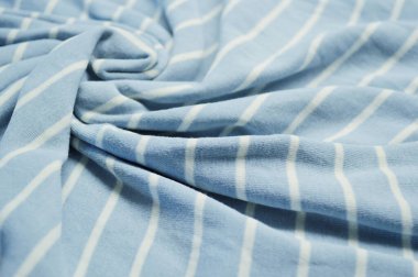 Arka plan olarak beyaz ince çizgili tekstil desenli mavi. Mavi 'ye beyaz çizgili kumaş kumaş kumaşı ile yaklaş. Buruşmuş kumaş dokusu