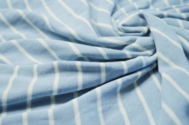 Arka plan olarak beyaz ince çizgili tekstil desenli mavi. Mavi 'ye beyaz çizgili kumaş kumaş kumaşı ile yaklaş. Buruşmuş kumaş dokusu