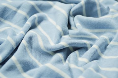 Arka plan olarak beyaz ince çizgili tekstil desenli mavi. Mavi 'ye beyaz çizgili kumaş kumaş kumaşı ile yaklaş. Buruşmuş kumaş dokusu