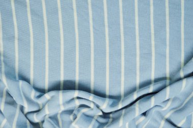 Arka plan olarak beyaz ince çizgili tekstil desenli mavi. Mavi 'ye beyaz çizgili kumaş kumaş kumaşı ile yaklaş. Buruşmuş kumaş dokusu