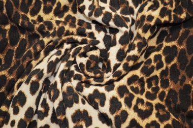 Arka plan olarak leopar desenli tekstil. Leopar desenli kumaşa yakın çekim yap. Buruşmuş kumaş dokusu