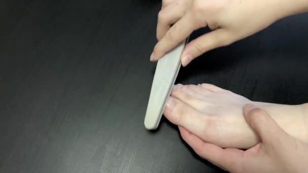女は爪をファイルで磨く足を閉じて 自宅で自分のためにペディキュアを作る 衛生とネイルケア 美容方法 — ストック動画