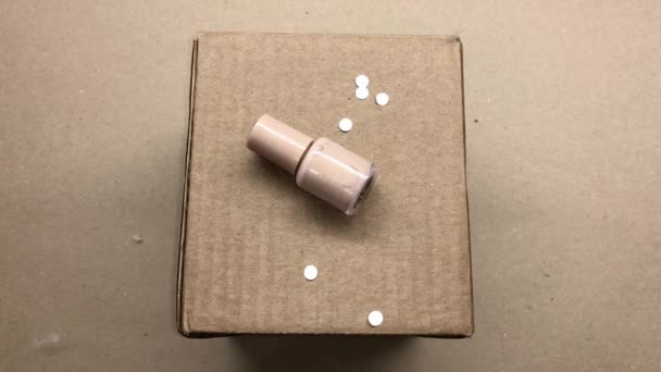 Witte Confetti Wordt Bovenop Een Glazen Pot Met Beige Nagellak — Stockvideo