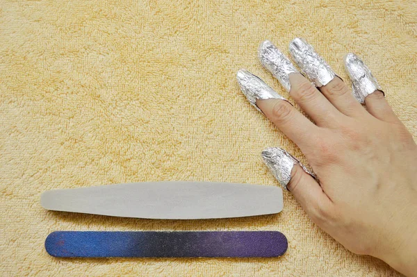 Quitar la goma laca de las uñas. dedos con papel de aluminio y lima de uñas en toalla beige — Foto de Stock