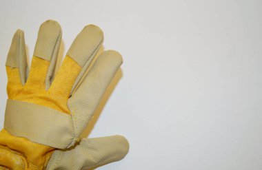 Beyaz bir arka plan karşısında bej ve sarı iş bezi eldiveni.