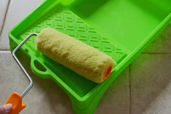 Paint roller in green plastic tray on ceramic tile background — Stock Photo, Image