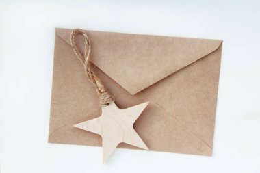Brown paper envelope of Kraft paper and wooden, Christmas, Christmas tree toy-star on a white background. The concept of greetings in the New year. The view from the top. Flatly.