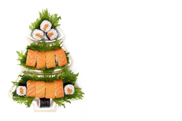 Noel 'de suşi konsepti. Beyaz bir tabakta suşi, beyaz bir arka planda Noel ağacı şeklinde. Japon restoranı için yaratıcı bir fikir. Düz. Tepeden manzara. Kopyalama alanı.