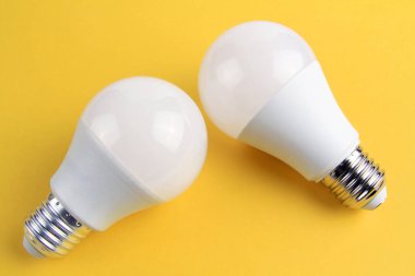 Sarı arka planda beyaz mat renginde iki elektrikli parlak lamba..