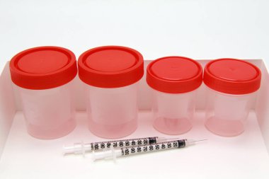 Kırmızı kapaklı plastik tıbbi kaplar, sıra sıra dizilmiş şırıngalar. Tıbbi araştırma kavramı, klinik laboratuvarlarda yapılan testler..