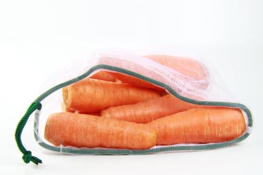 Beyaz bir yüzeyde, tekrar kullanılabilir çevre dostu bir bez torbada turuncu taze havuçlar. Sıfır atık konsepti, naylon poşet almak yok, bahçe işleri yok..