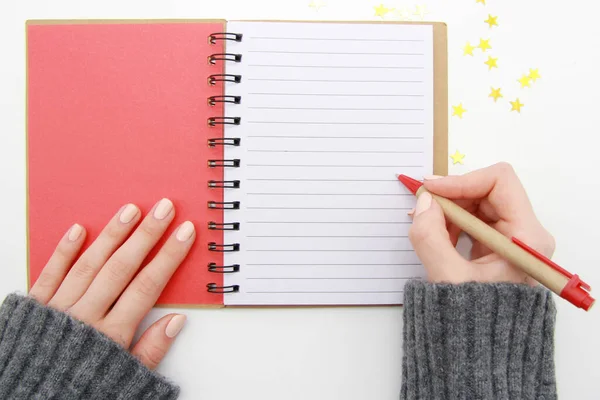 Kız elinde boş çarşaflı bir defter ve beyaz bir arka planda bir kalem tutuyor. Not defterine birinci şahıs olarak yazma, planlama, yapılacaklar listesi yapma kavramı..