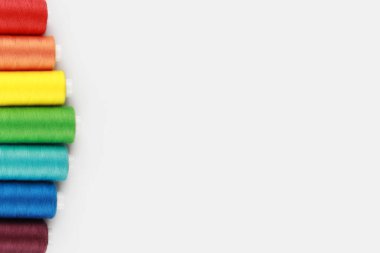 Renkli, gökkuşağı iplikleri (kırmızı, turuncu, sarı, yeşil, açık mavi, mavi, mor) iğneyle dikmek için. El işi kavramı. Üst Manzara. Flatlay. Kopyalama alanı.