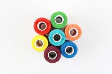 Renkli, yanardöner iğne iplikleri, beyaz arka planda bir çiçek şeklinde katlanmış. El yapımı konsept, giysi tamiri. Üst Manzara. Düz çizgi. Kopyalama alanı.