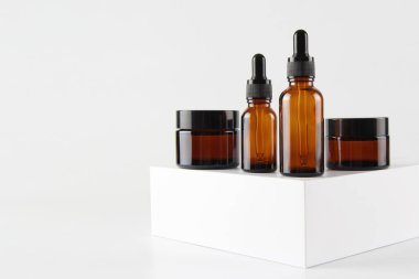 Beyaz arka planda camdan yapılmış boş bir cam damlatıcı şişesi ve krema kavanozunun maketi. Serum, cilt bakım kremi, pankart ya da şablon. Doğal kozmetik ürünleri konsepti..