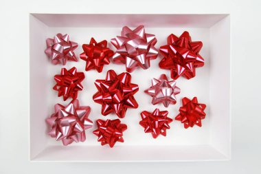 Beyaz bir kutuda bir sürü güzel, kırmızı, pembe tatil yayı, beyaz bir arka plandaki hediye kutusuna ilave. Hediye paketi mağazada, tatiller için hazırlanıyor..