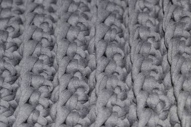 Gri tuval, örgü örme, iplik örgüsü. Yoğun, üç boyutlu desen. El yapımı konsept, hobi, çevrimiçi moda öğeleri örme kursu, iç mekan ögeleri, çantalar, halı.