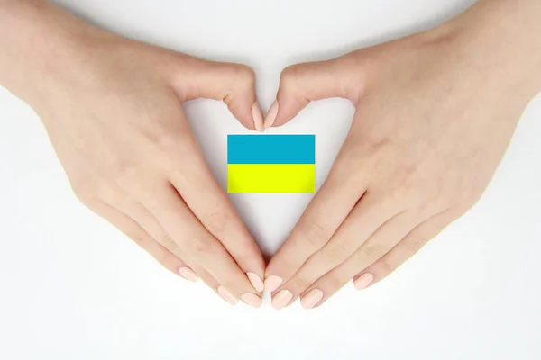 Female hands creating a heart inside the flag of Ukraine on a white background.Background for a postcard on Flag Day, Independence Day, travel, patriotism, other holiday with space for text
