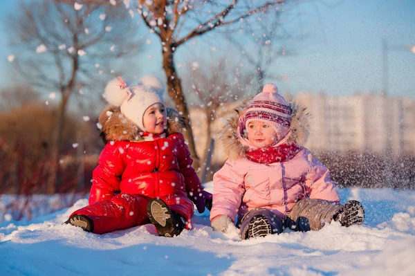 雪の吹きだまりで遊んで笑って winterwear の幸せな子供たち ロイヤリティフリーのストック画像