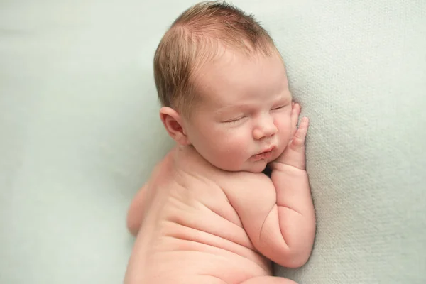 Picture of a newborn baby curled up sleeping on a blanket — Stock Photo, Image