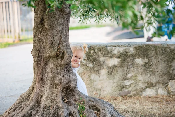 Cute girl hiding behind a tree — Stock Photo, Image