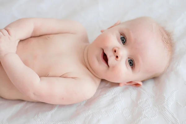 Imádnivaló baba fiú az ágyon az ő oldalán portréja — Stock Fotó