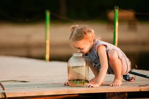 Niño feliz con un pez que atrapó junto a un estanque — Foto de Stock