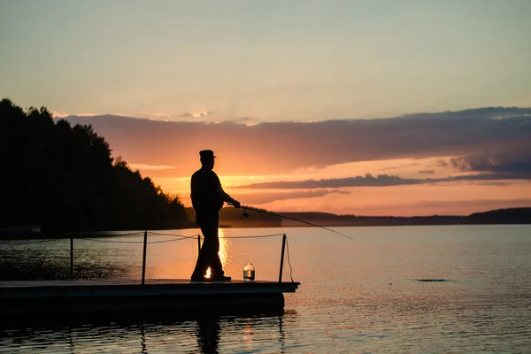 Man fishing on a lake from the bridge at sunset — Stock Photo © flas88  #58739943
