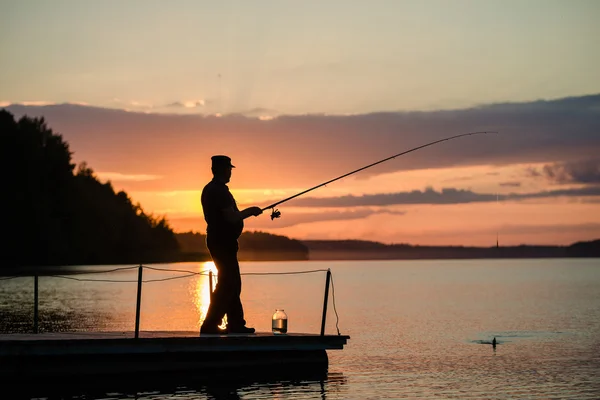 男は日没時、橋の上から湖の釣り ロイヤリティフリーのストック写真