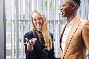 Ofis binasının dışında cep telefonu olan iş çifti