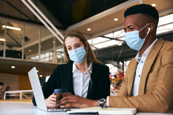 Modern Ofis 'te Sağlık Salgını sırasında laptoplarını kullanarak maske takan bir çift.
