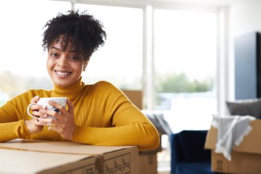Kendine güvenen genç bir kadının portresi. Yeni evinde dinleniyor ve taşınma gününde kahve içiyor.