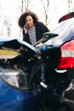 Trafik kazasından sonra hasarlı bir arabanın yanında duran genç bir kadın cep telefonu kullanan sigorta şirketine olay bildirdi.