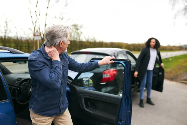 高齢男性と若い女性のドライバーは車から出て 道路交通事故後の損傷を検査します — ストック写真