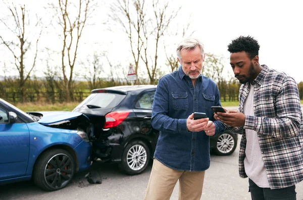 交通事故後の自動車保険の詳細を携帯電話で交換する道路脇の若いドライバーや高齢者 — ストック写真