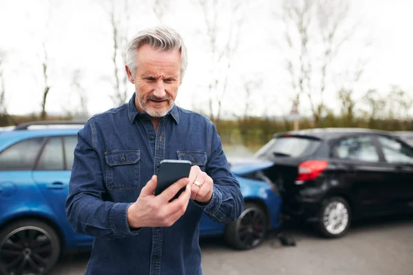 交通事故後に破損車で立っているシニア男は 携帯電話を使用して故障復旧会社を呼び出します — ストック写真